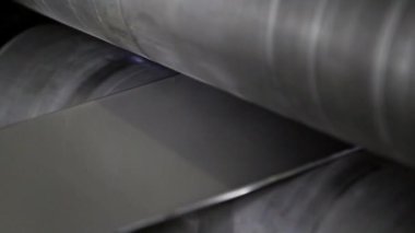 Yuvarlanan makinelerde paslanmaz çelikten metal şeritleri üretiliyor..