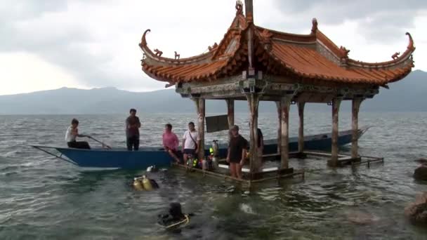 Divers sink under water to search for a sunken city in Fuxian Lake. — ストック動画