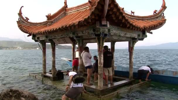 Personer nära lusthus med kinesiskt tak i Fuxian Lake. — Stockvideo