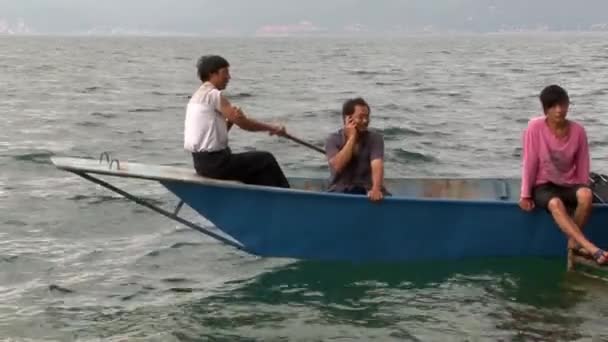 Orang Asia berbicara di telepon pada sampan Cina perahu di Danau Fuxian . — Stok Video