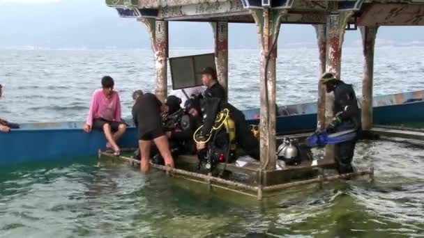 Los buceadores se preparan para bucear cerca de gazebo con techo de estilo chino en Fuxian Lake . — Vídeos de Stock