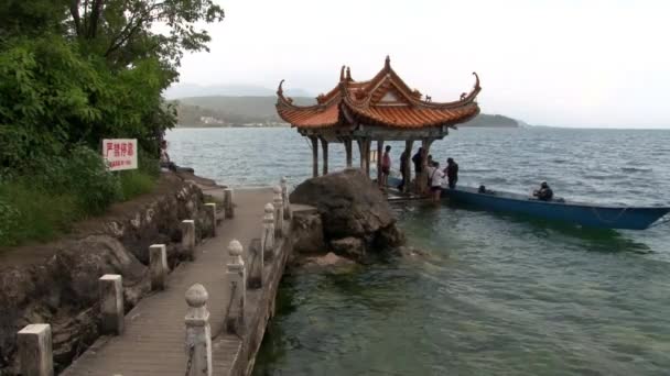 Plongeurs se préparent pour la plongée près du belvédère avec toit de style chinois dans le lac Fuxian . — Video