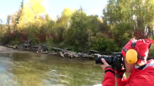 Frau mit Kamera im Motorboot fährt auf dem Lenafluss in der Taiga von Sibirien. — Stockvideo