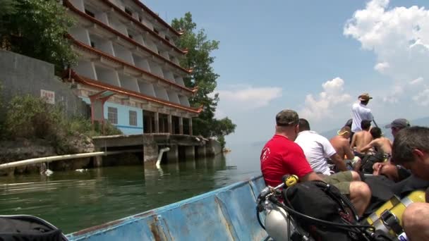 Водолази пливуть човном до місця занурення в озері Фуксіан.. — стокове відео