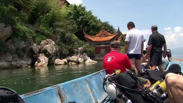 Dykare simmar på en båt till dykplatsen i Fuxian Lake. — Stockvideo