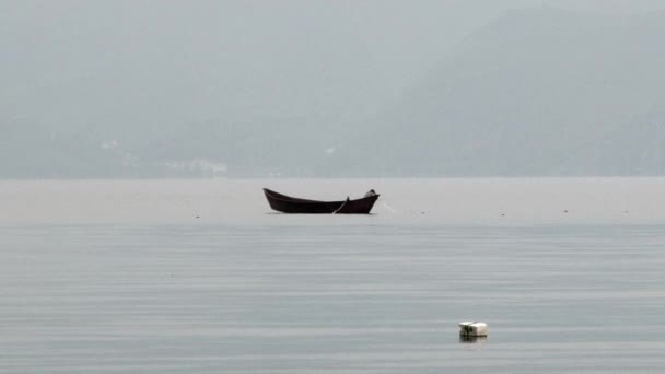 Pescador em barco captura peixe com rede de pesca no nevoeiro no Lago Fuxian, na China . — Vídeo de Stock