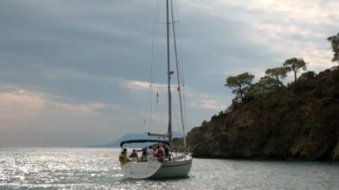 Mavi denizin arka planındaki beyaz yatlardaki insanlar ve gökyüzündeki bulutlar..