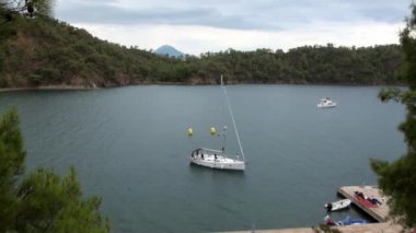 Koydaki rıhtıma doğru yüzen insanlarla dolu beyaz bir yat..