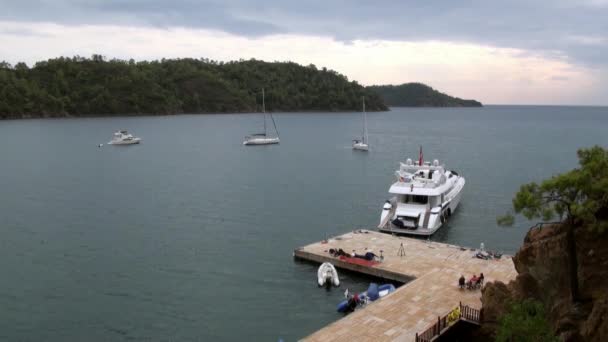 Yacht bianco con persone si trova vicino al molo nella baia. — Video Stock