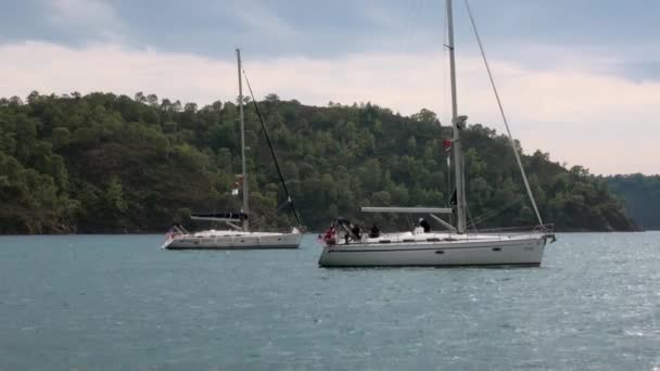 Mavi denizin arka planındaki beyaz yatlardaki insanlar ve gökyüzündeki bulutlar.. — Stok video