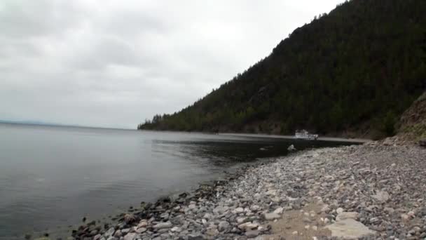 Yate cerca de la costa montañosa verde y piedras lisas del lago Baikal . — Vídeo de stock