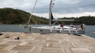 İskeleye yüzen insanlarla dolu beyaz bir yat..