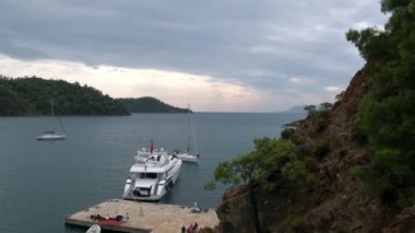 Körfezdeki rıhtımın yanında duran beyaz yatta insanlar var..