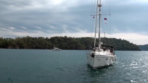 青い海と空の雲を背景に白いヨットに乗っている人々. — ストック動画