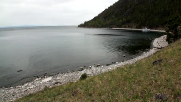 Yacht nära gröna bergiga kusten och släta stenar i sjön Baikal. — Stockvideo