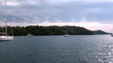 Mavi denizin arka planında beyaz yatlar ve gökyüzünde bulutlar.