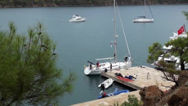 Yacht bianco con persone si trova vicino al molo nella baia. — Video Stock