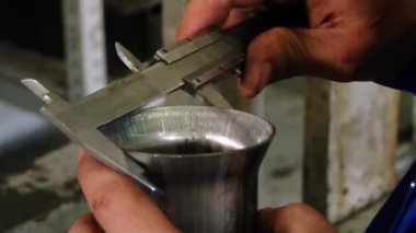 İşçilerin elleri fabrikada kalibre ile borunun kalınlığını ölçer..