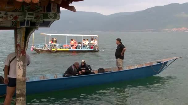 Los buceadores se preparan para bucear cerca de gazebo con techo de estilo chino en Fuxian Lake . — Vídeo de stock