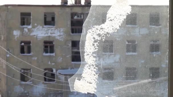 Nieve en una rota ventana congelada de casa abandonada en ciudad desierta . — Vídeo de stock