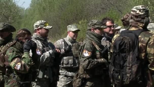 Airsoft team in militair uniform met een wapen op de achtergrond van bos. — Stockvideo