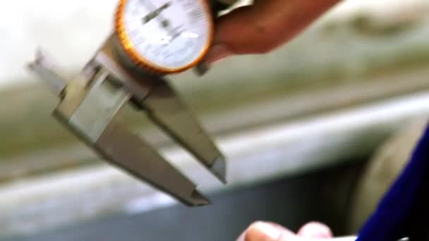 Рабочие руки измеряют толщину труб с помощью суппорта на заводе. — стоковое видео
