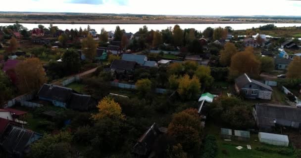 Wideo z lotu ptaka Wioska z domami i ogrodami nad rzeką otoczona zielonymi pastwiskami z przepięknym krajobrazem z widokiem na kino. Concept climate outdoor nature. — Wideo stockowe