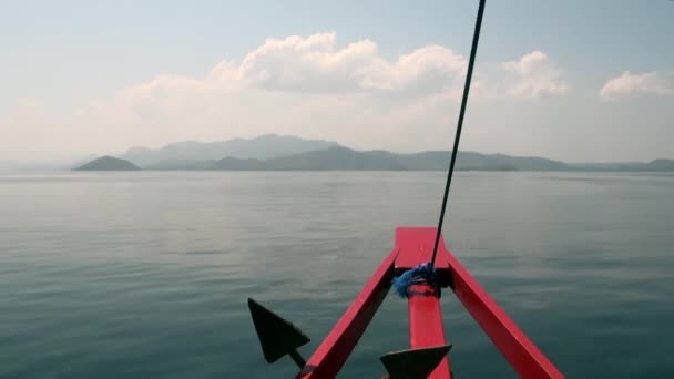 Arc rouge du navire en mouvement sur fond de surface de la mer et des îles de montagne . — Video