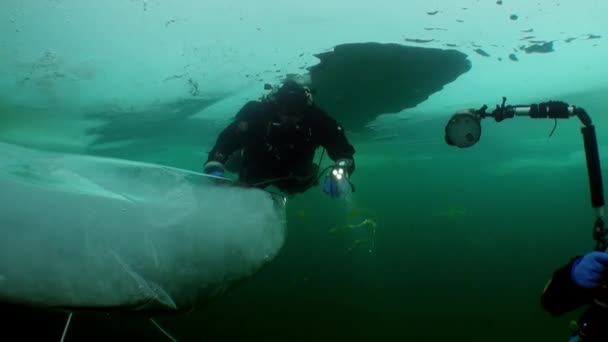 バイカルの氷の下で水中カメラマンや技術ダイバーの極端なダイビング. — ストック動画