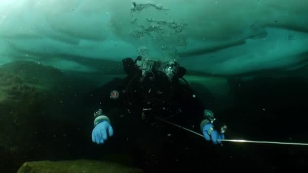 Unterwasserkameramann mit Kamera und Taucher unter dem Eis des Baikalsees. — Stockvideo