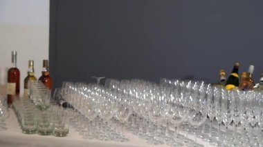 Birçok cam kadehler gri duvarın arkasındaki ziyafet masasında parlıyor..