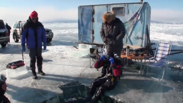 Dykare är nedsänkta under vatten i ishålet i sjön Baikal. — Stockvideo