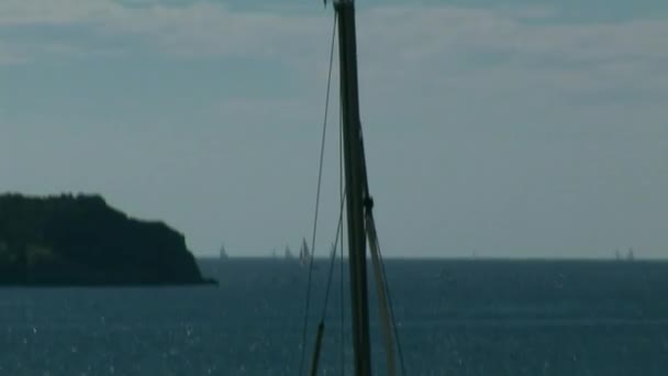 L'homme est assis sur le mât du yacht sur fond de ciel bleu . — Video