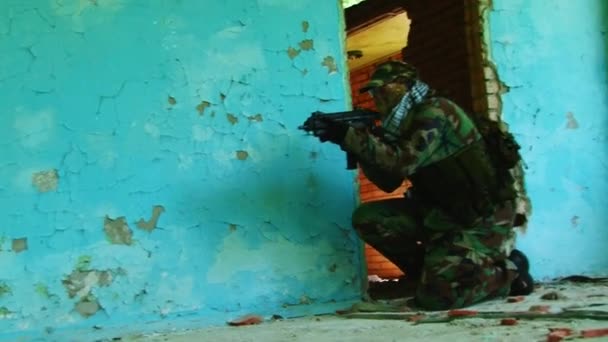 Airsoft-Teamspiel mit Waffe steht in der Nähe eines zerstörten Hauses. — Stockvideo