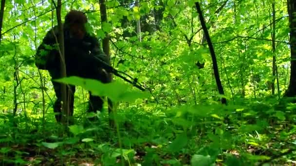 Airsoft speler in militair uniform met wapen in het bos. — Stockvideo