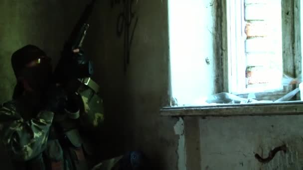 Askeri üniformalı asker harabe evin camından dışarı ateş ediyor.. — Stok video