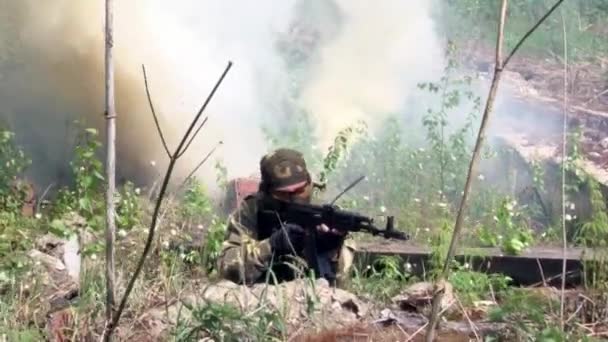 Airsoft speler in militair uniform met wapen schieten in de buurt van geruïneerd huis. — Stockvideo