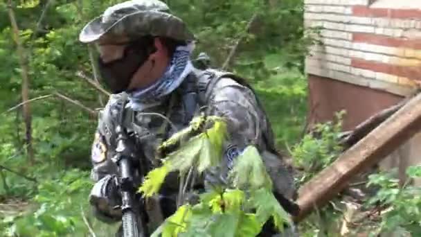 Airsoft hráč ve vojenské uniformě se zbraní v blízkosti zničeného domu. — Stock video