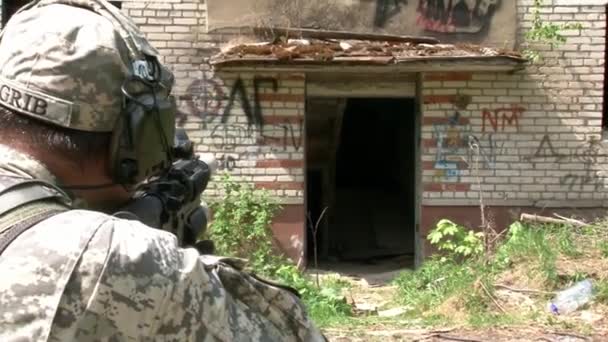 Повітряний м'який гравець у військовій формі зі зброєю біля зруйнованого будинку.. — стокове відео