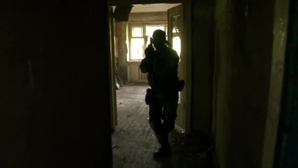 Airsoft hráč ve vojenské uniformě se zbraní v troskách domu. — Stock video
