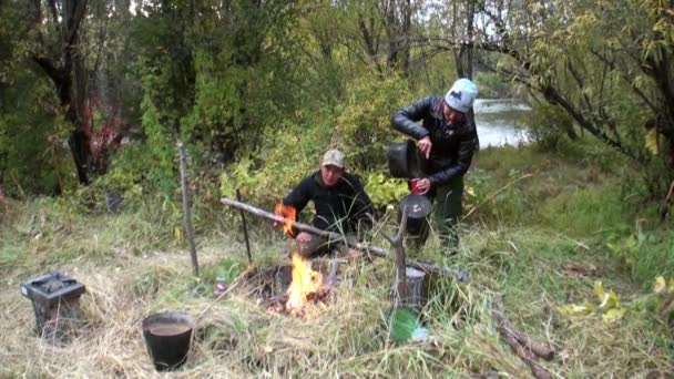 River fish is fried on fire near bowler. — Stock Video