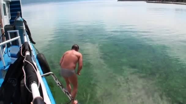 L'homme saute du bateau à l'eau et nage dans le lac Baïkal . — Video