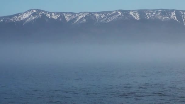 Waves on water surface on background of dark sky and gray clouds at sunset. — Stock Video