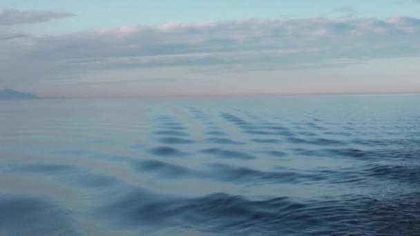 Vågor på vattenytan på bakgrunden av mörk himmel och grå moln vid solnedgången. — Stockvideo