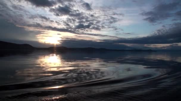 Ondas na superfície da água no fundo do céu escuro e nuvens cinzas ao pôr do sol. — Vídeo de Stock