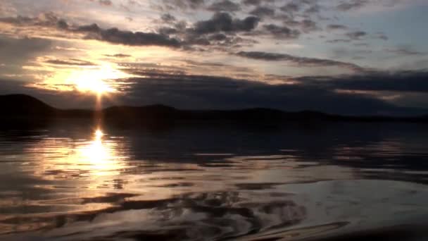 Ondas na superfície da água no fundo do céu escuro e nuvens cinzas ao pôr do sol. — Vídeo de Stock