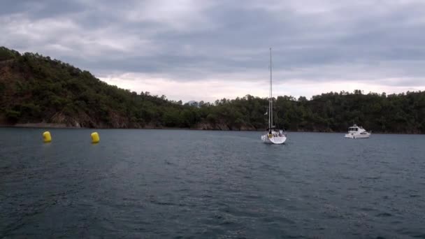 Bateau blanc navigue sur fond de mer et de montagnes sur la côte en baie. — Video