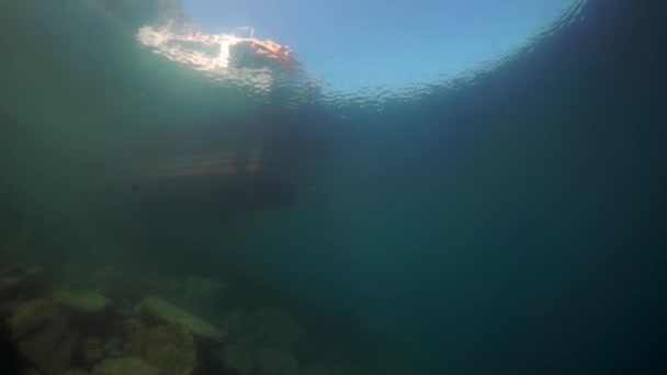 Underwater shooting of diver jumping into water from boat on Baikal. — Stock Video