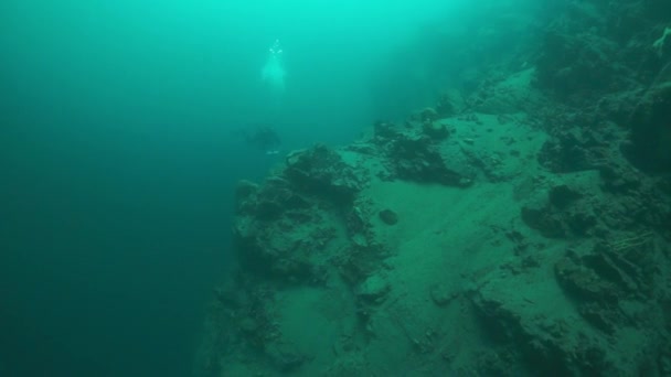 Дайвер с камерой, плавающий глубоко под водой в озере Байкал . — стоковое видео