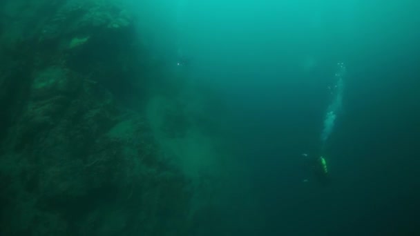 Silhouet van duiker met camera bij stenen onder water in het Baikalmeer. — Stockvideo